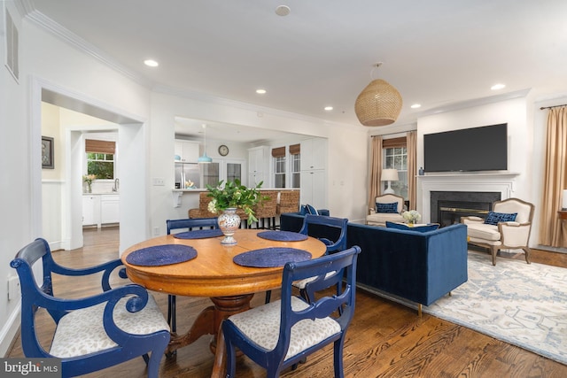 dining room featuring a glass covered fireplace, crown molding, and wood finished floors