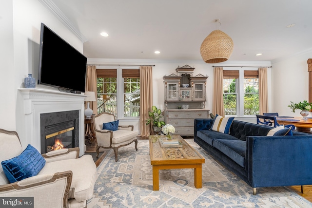 living area with recessed lighting, crown molding, and a glass covered fireplace