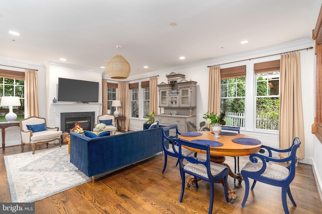 living room featuring recessed lighting, ornamental molding, wood finished floors, and a glass covered fireplace