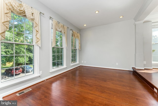 spare room with hardwood / wood-style flooring and decorative columns