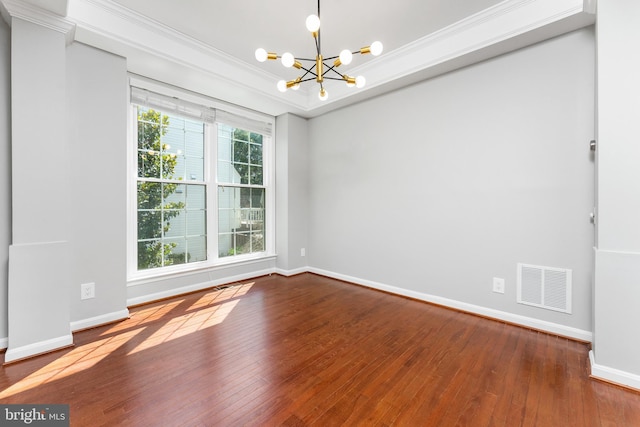 spare room featuring hardwood / wood-style flooring, a tray ceiling, crown molding, and a notable chandelier