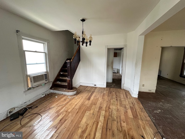 unfurnished room featuring wood-type flooring, a notable chandelier, and cooling unit