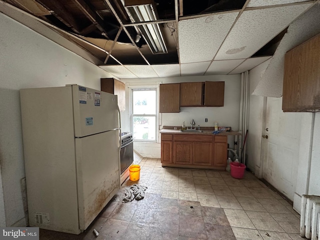 kitchen featuring sink, a drop ceiling, and white appliances