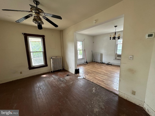 unfurnished room featuring ceiling fan with notable chandelier, hardwood / wood-style floors, and radiator