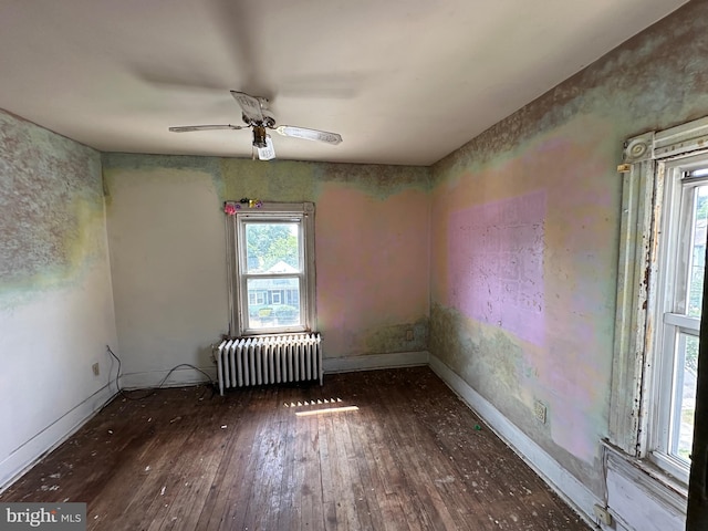 empty room with radiator, dark wood-type flooring, and ceiling fan