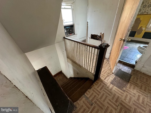 stairway featuring parquet flooring