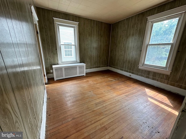 unfurnished room featuring radiator heating unit, wood walls, and light wood-type flooring