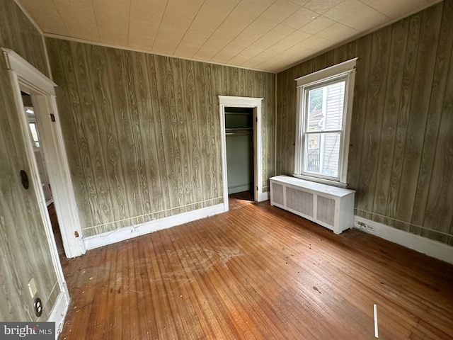 interior space featuring radiator, a closet, wood-type flooring, and wood walls