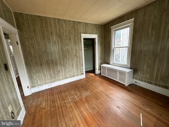 interior space with hardwood / wood-style floors, radiator heating unit, a closet, and wooden walls