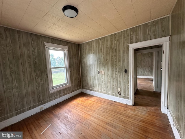 spare room featuring wood walls and hardwood / wood-style flooring