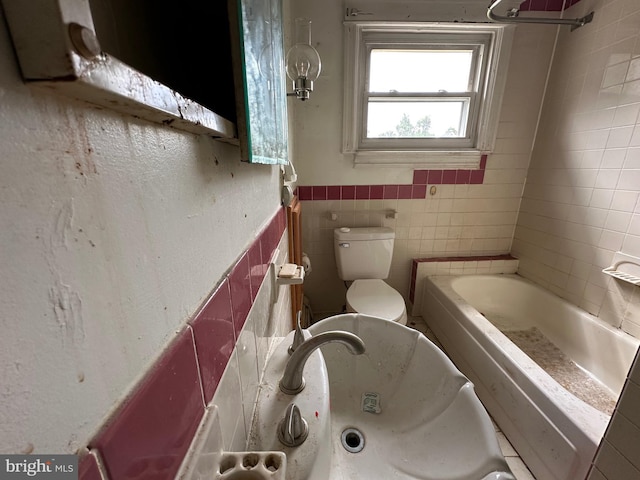 bathroom featuring toilet, tile walls, a bathtub, and sink