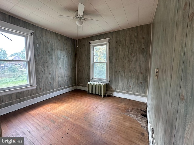 empty room with radiator, ceiling fan, plenty of natural light, and hardwood / wood-style floors