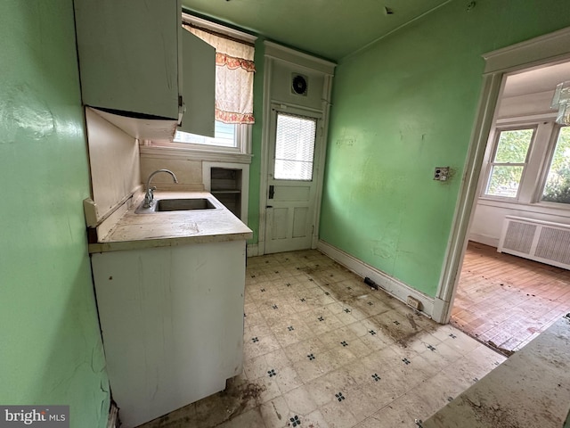 kitchen featuring green cabinetry, radiator heating unit, and sink