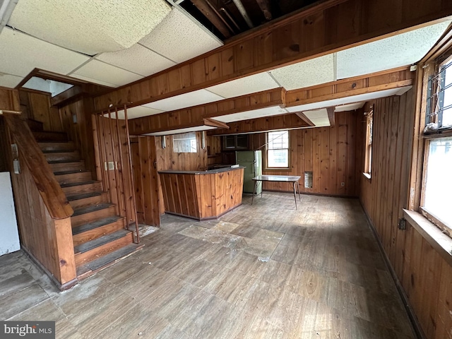 basement with a drop ceiling and wooden walls