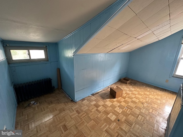 additional living space featuring light parquet floors, radiator heating unit, and wood walls