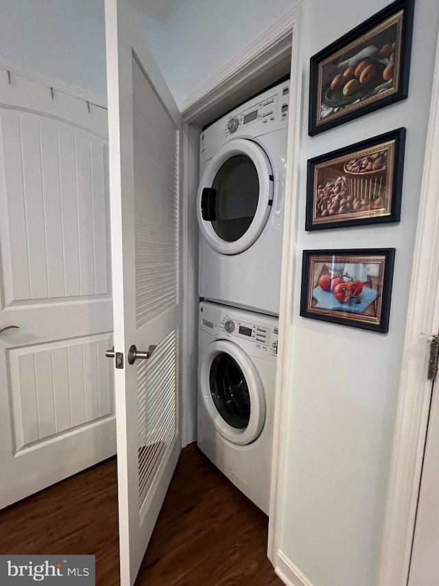 clothes washing area with stacked washer and dryer and dark hardwood / wood-style floors