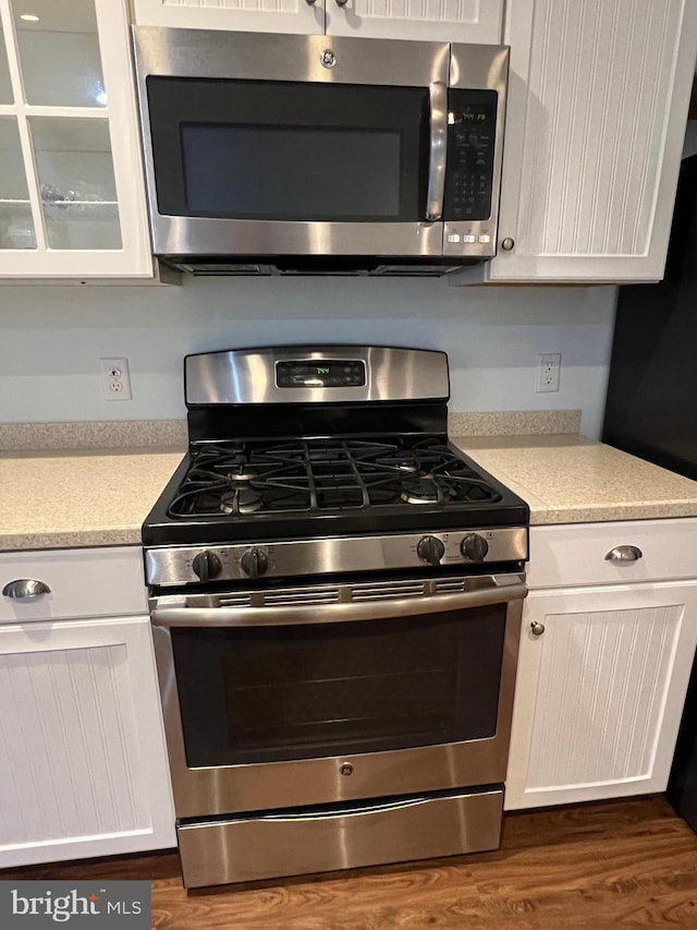 kitchen with white cabinets, stainless steel appliances, and dark wood-type flooring