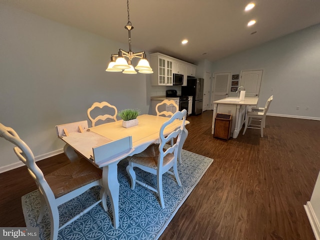 dining room with dark hardwood / wood-style flooring, vaulted ceiling, a notable chandelier, and sink