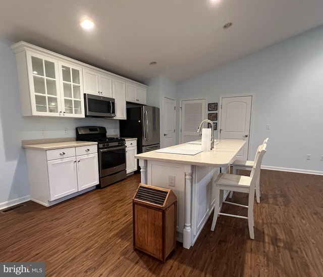 kitchen featuring an island with sink, white cabinets, stainless steel appliances, and dark hardwood / wood-style floors