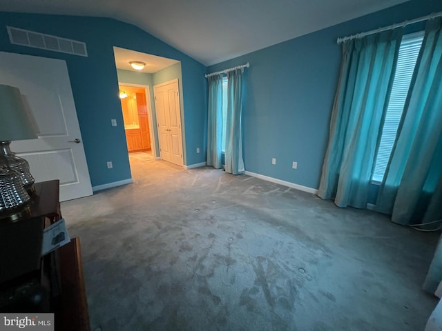 carpeted bedroom featuring connected bathroom and vaulted ceiling