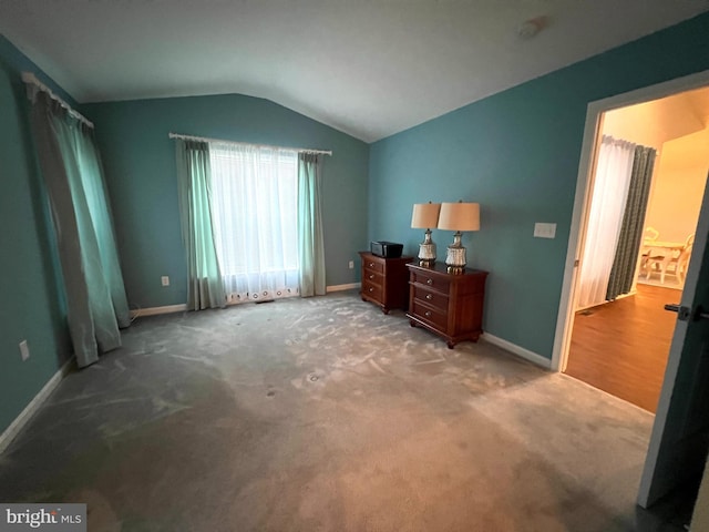 bedroom with carpet flooring, ensuite bathroom, and vaulted ceiling