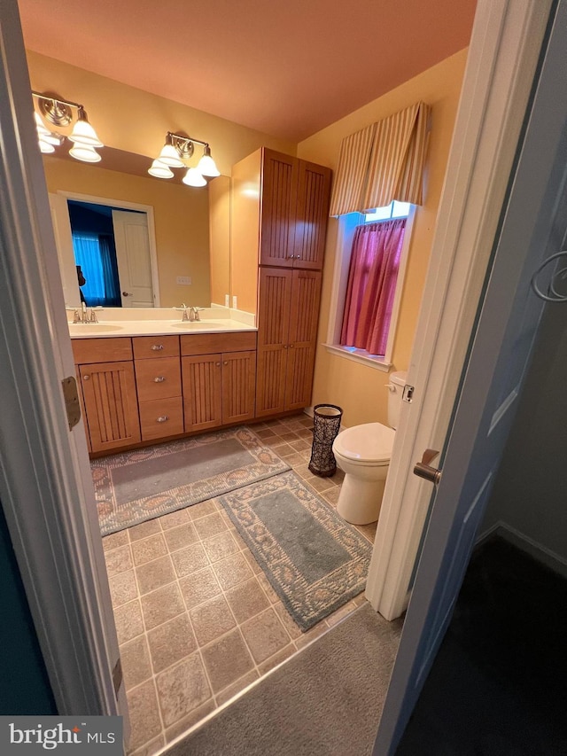 bathroom with a notable chandelier, vanity, and toilet