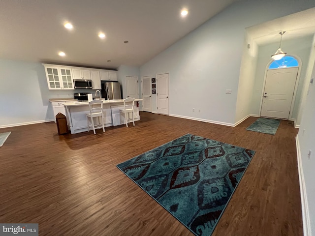 living room with sink, dark wood-type flooring, and high vaulted ceiling