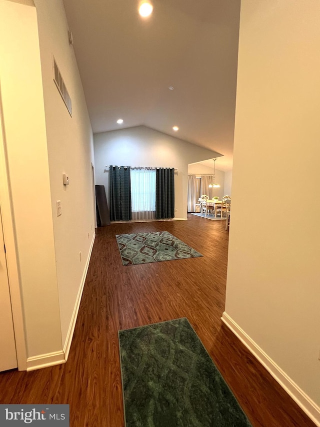 corridor with dark hardwood / wood-style flooring and vaulted ceiling