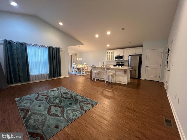 living room featuring vaulted ceiling, dark wood-type flooring, and a notable chandelier