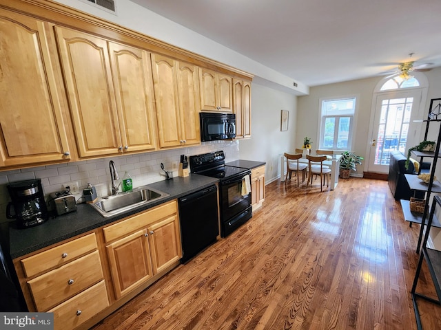 kitchen with hardwood / wood-style flooring, black appliances, sink, decorative backsplash, and ceiling fan