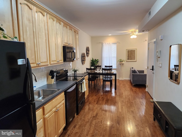 kitchen featuring black appliances, light brown cabinetry, hardwood / wood-style flooring, ceiling fan, and backsplash