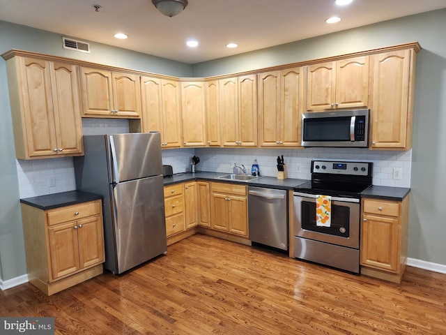 kitchen with hardwood / wood-style flooring, sink, decorative backsplash, and stainless steel appliances