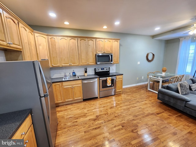 kitchen featuring tasteful backsplash, stainless steel appliances, sink, light wood-type flooring, and ceiling fan