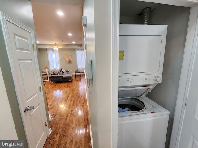 laundry area with stacked washer / dryer, ceiling fan, and light hardwood / wood-style flooring