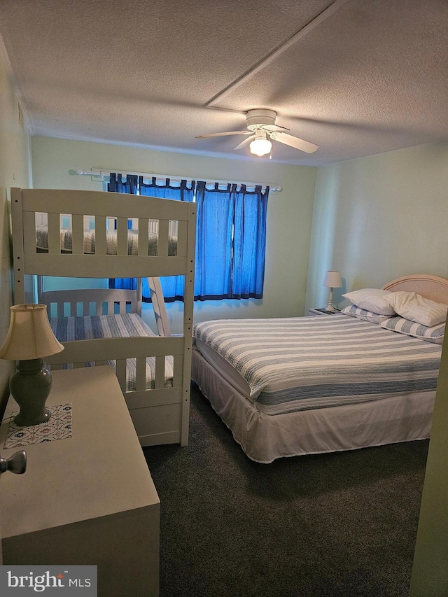 bedroom with ceiling fan, dark carpet, and a textured ceiling