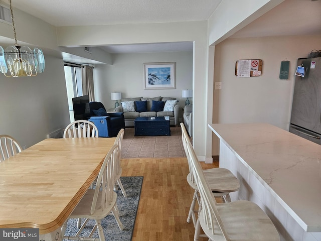 dining area featuring an inviting chandelier, a textured ceiling, and light wood-type flooring