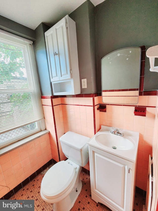 bathroom with tile patterned floors, vanity, tile walls, and toilet