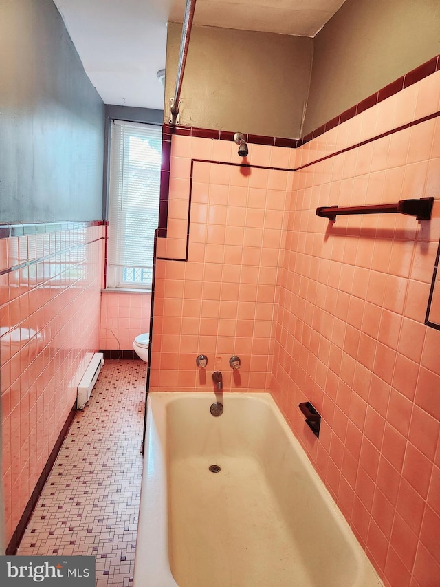 bathroom featuring baseboard heating, a tub to relax in, tile walls, and toilet