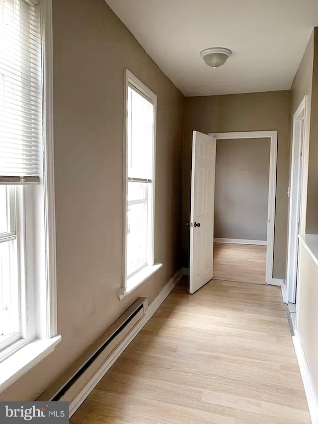 corridor with light wood-type flooring and baseboard heating