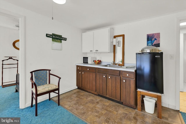 kitchen featuring white cabinets, fridge, and sink