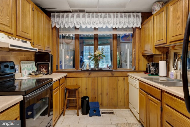 kitchen featuring sink, black electric range oven, light tile patterned flooring, white dishwasher, and a drop ceiling