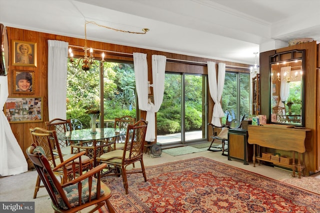 interior space featuring carpet floors, a notable chandelier, wood walls, and crown molding