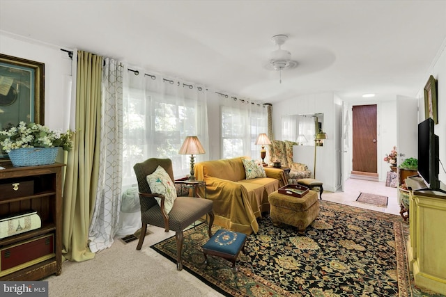 living area with ceiling fan, ornamental molding, and carpet floors