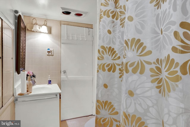 bathroom with tile walls, walk in shower, and vanity