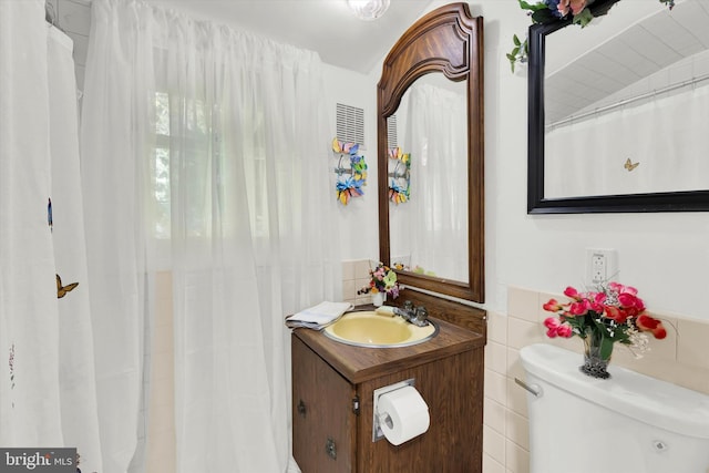 bathroom with toilet, tile walls, and vanity