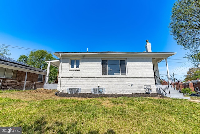 rear view of house with central AC unit and a lawn