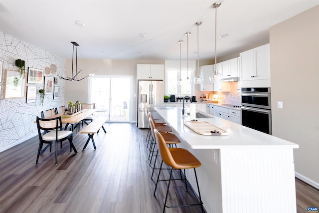 kitchen featuring appliances with stainless steel finishes, a kitchen breakfast bar, sink, a center island with sink, and white cabinetry