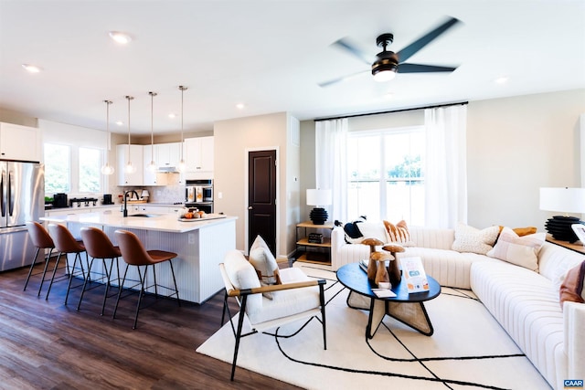 living room featuring dark hardwood / wood-style flooring, ceiling fan, and sink