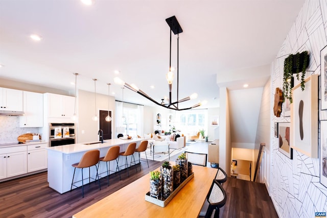 dining area with sink, dark hardwood / wood-style flooring, and an inviting chandelier