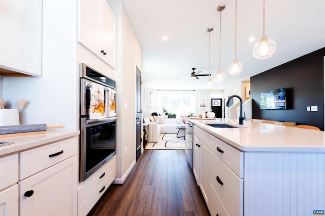 kitchen with white cabinetry, ceiling fan, stainless steel appliances, an island with sink, and pendant lighting